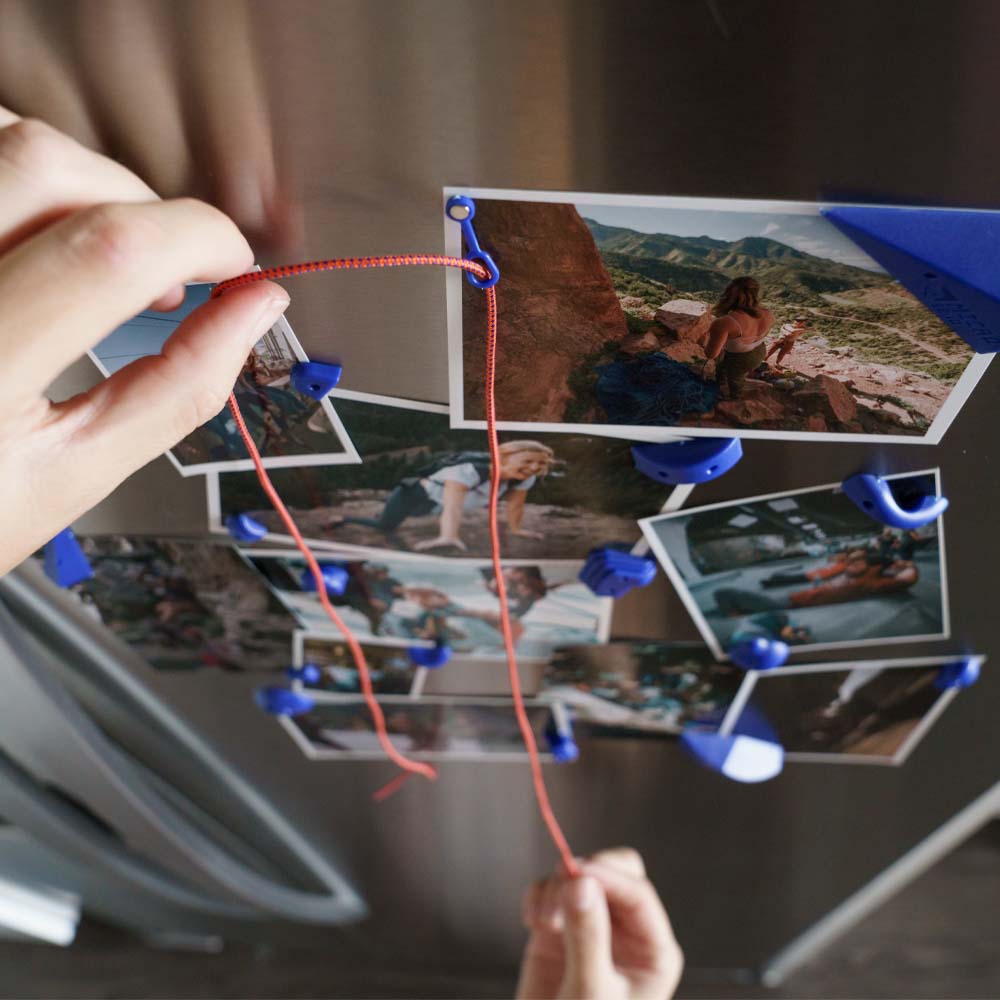 Hands pulling small rope through small carabiner on fridge