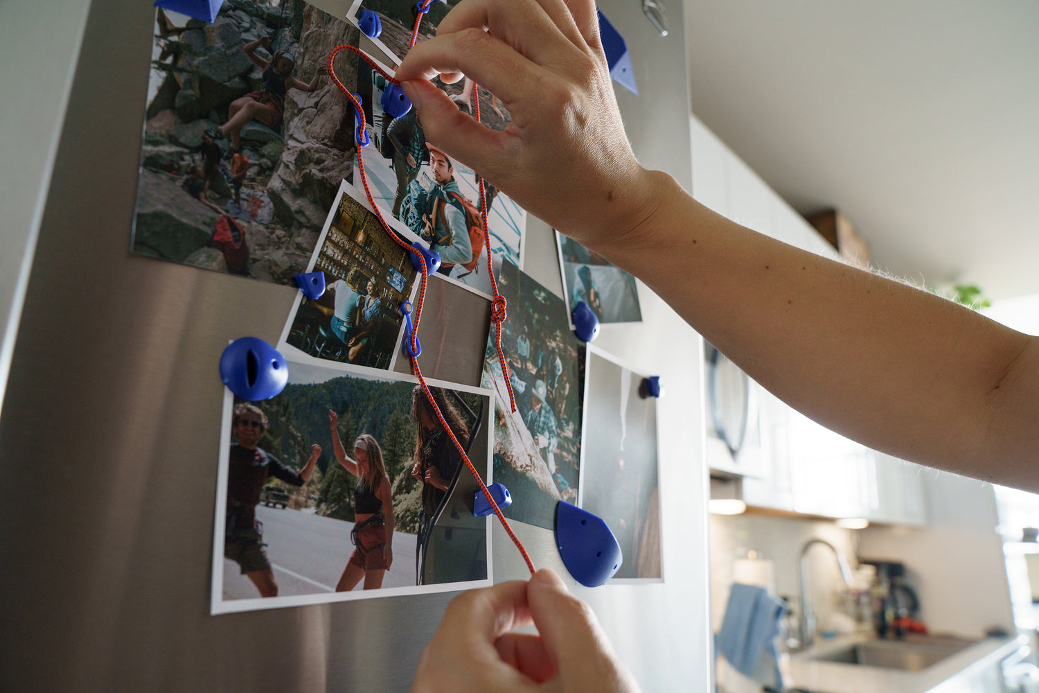 Hands placing pictures on fridge with MicroSend magnets