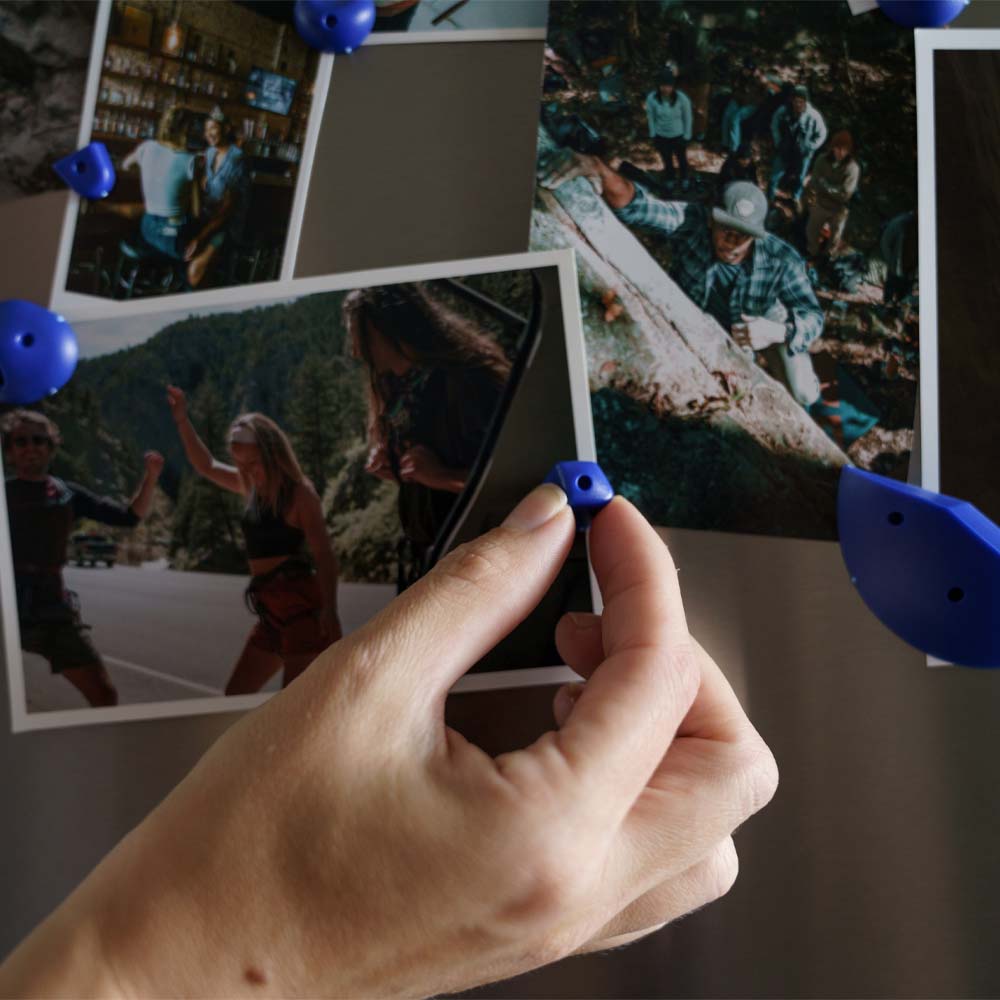 Hand placing blue micro send piece over photos on fridge