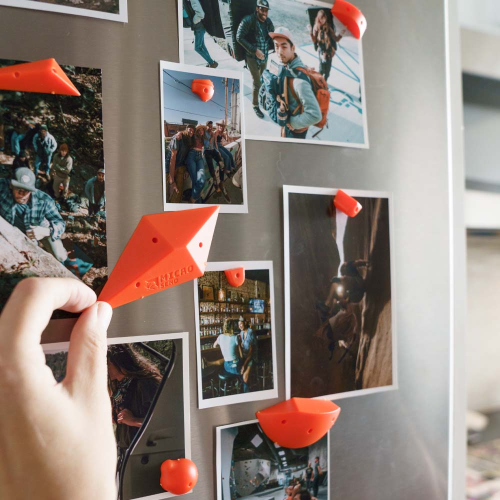 Hands placing orange micro send holds over photos on fridge